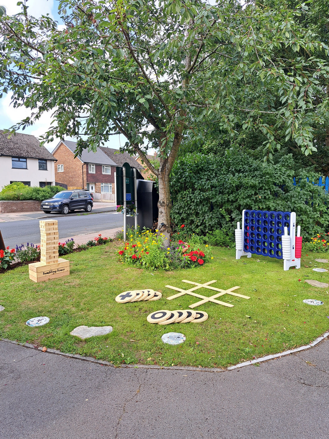 3 garden games - giant versions of jenga, connect 4 & noughts & crosses - set up on a grassy lawn under a tree and houses in the background