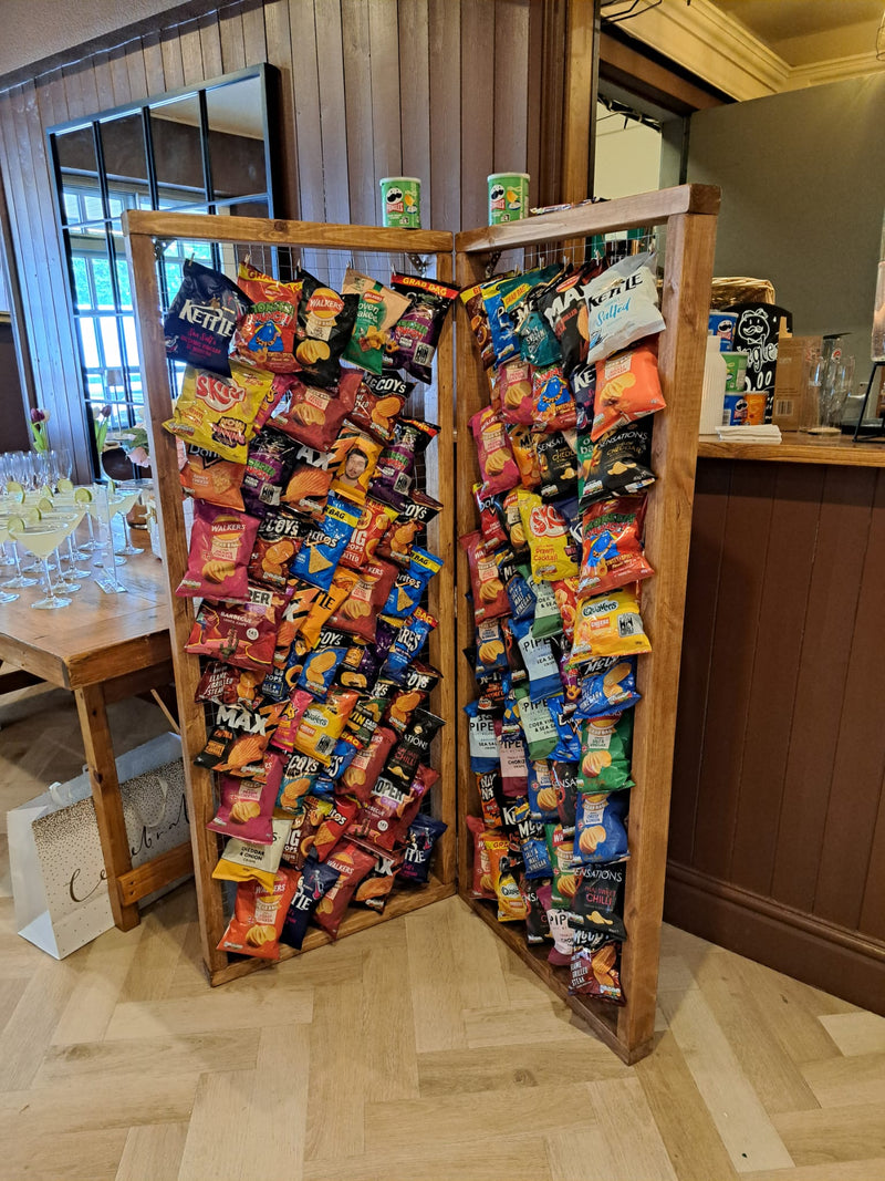 Wooden snack display with various colorful packets in a room setting.