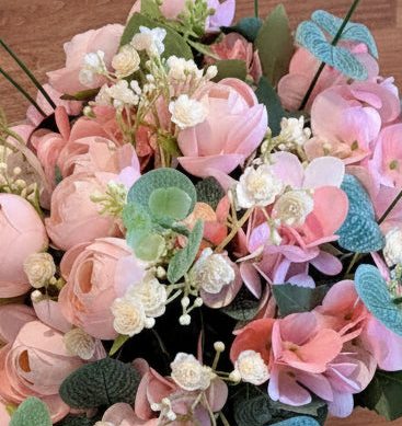 A close up of a bouquet with pink flowers and green foliage