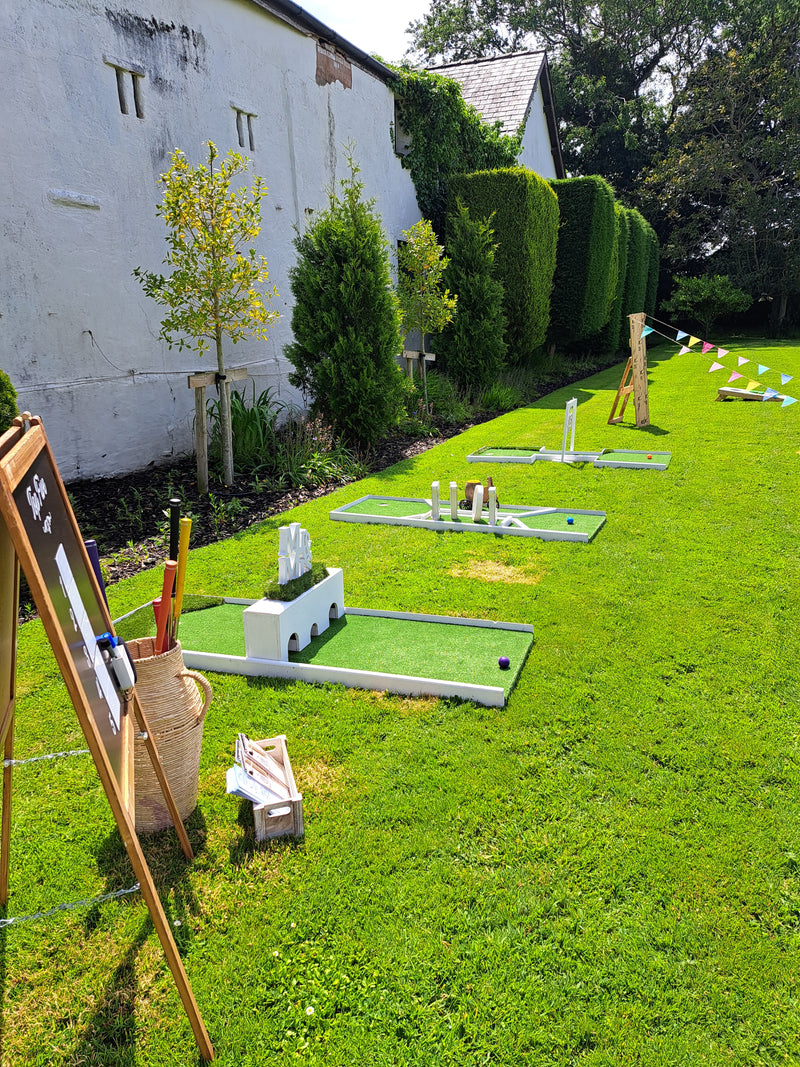 Wedding mini golf area with green grass and white obstacles against a white building on a lawn. Riverbarn, Poulten le Fylde